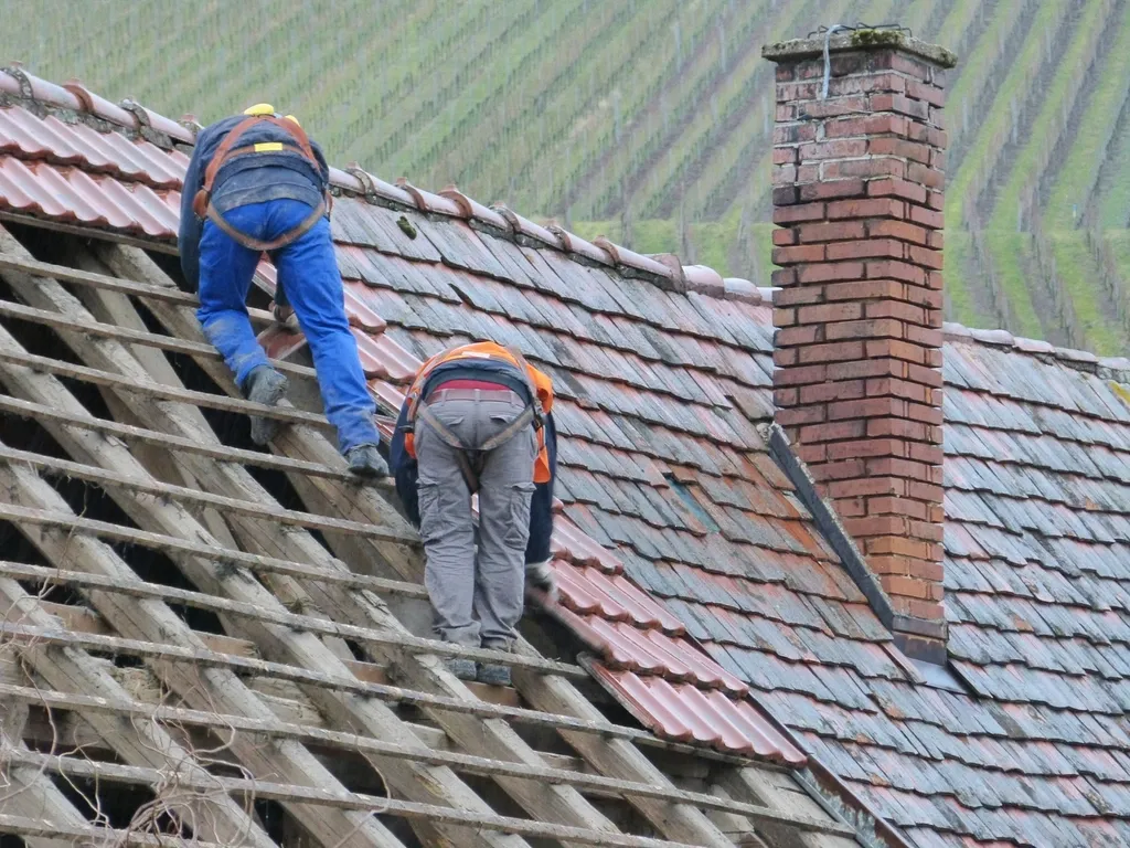 Two roofers working on a tiled roof